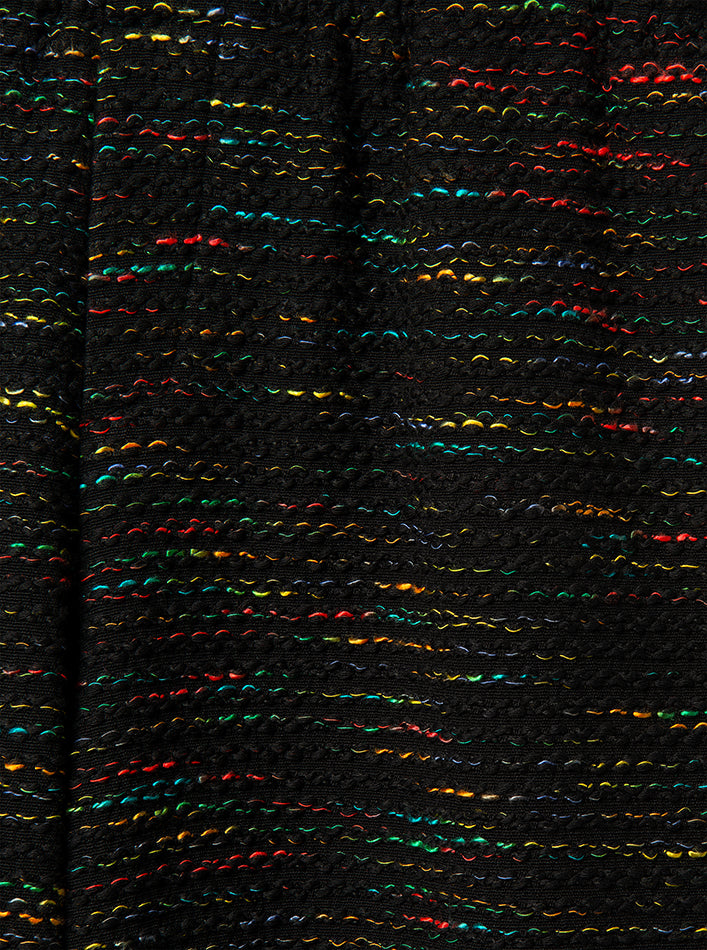 Close-up of a textured fabric with multicolored threads on a black background