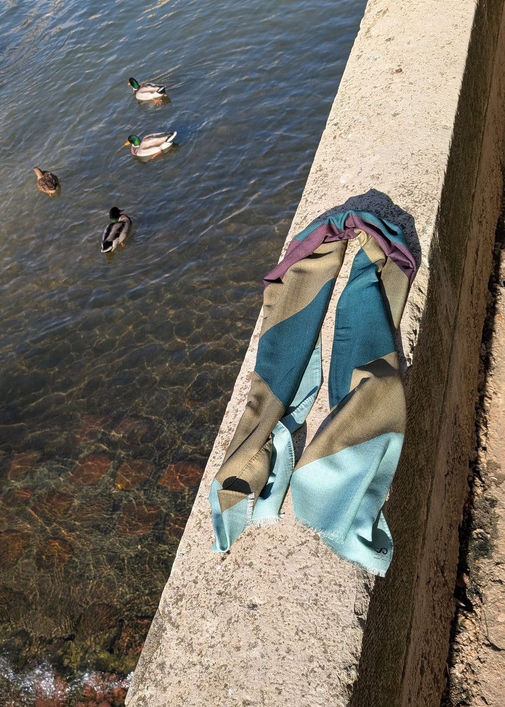 geometric wool scarf in green tones and brown laying by the Seine river