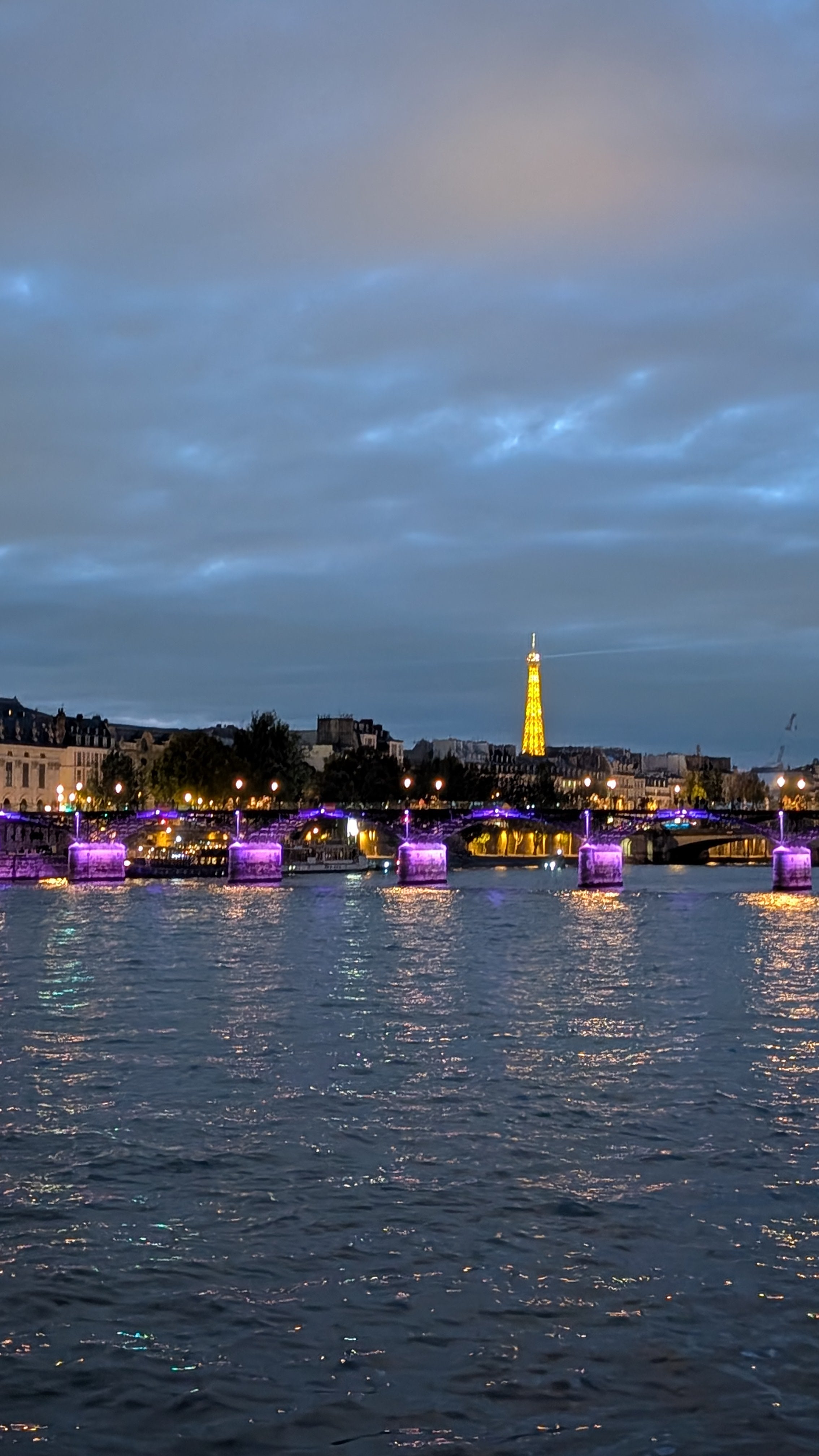 Cityscape with illuminated Eiffel Tower at night, viewed from across the .eine river
