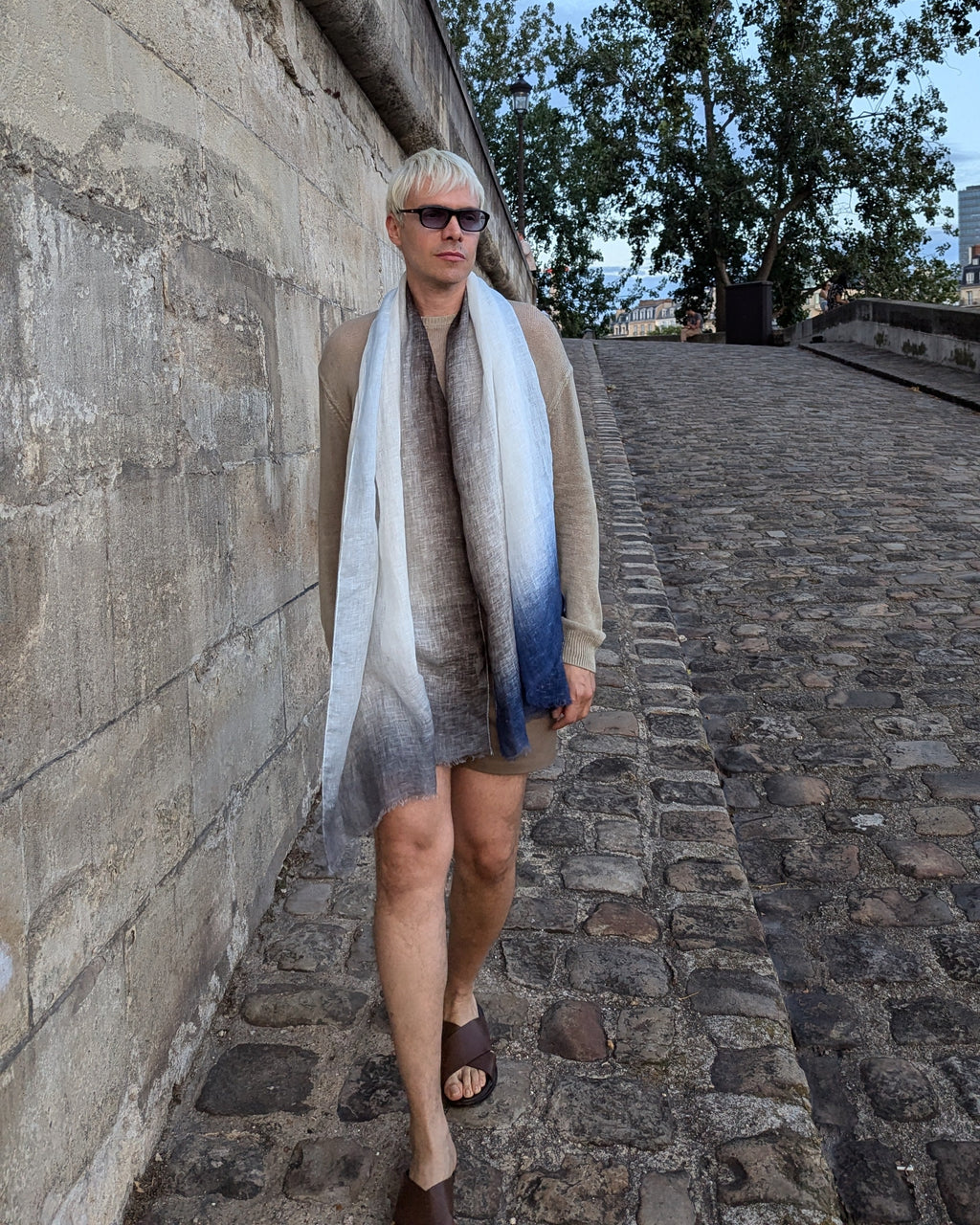model in beige wears linen scarf in blue, indigo and grey