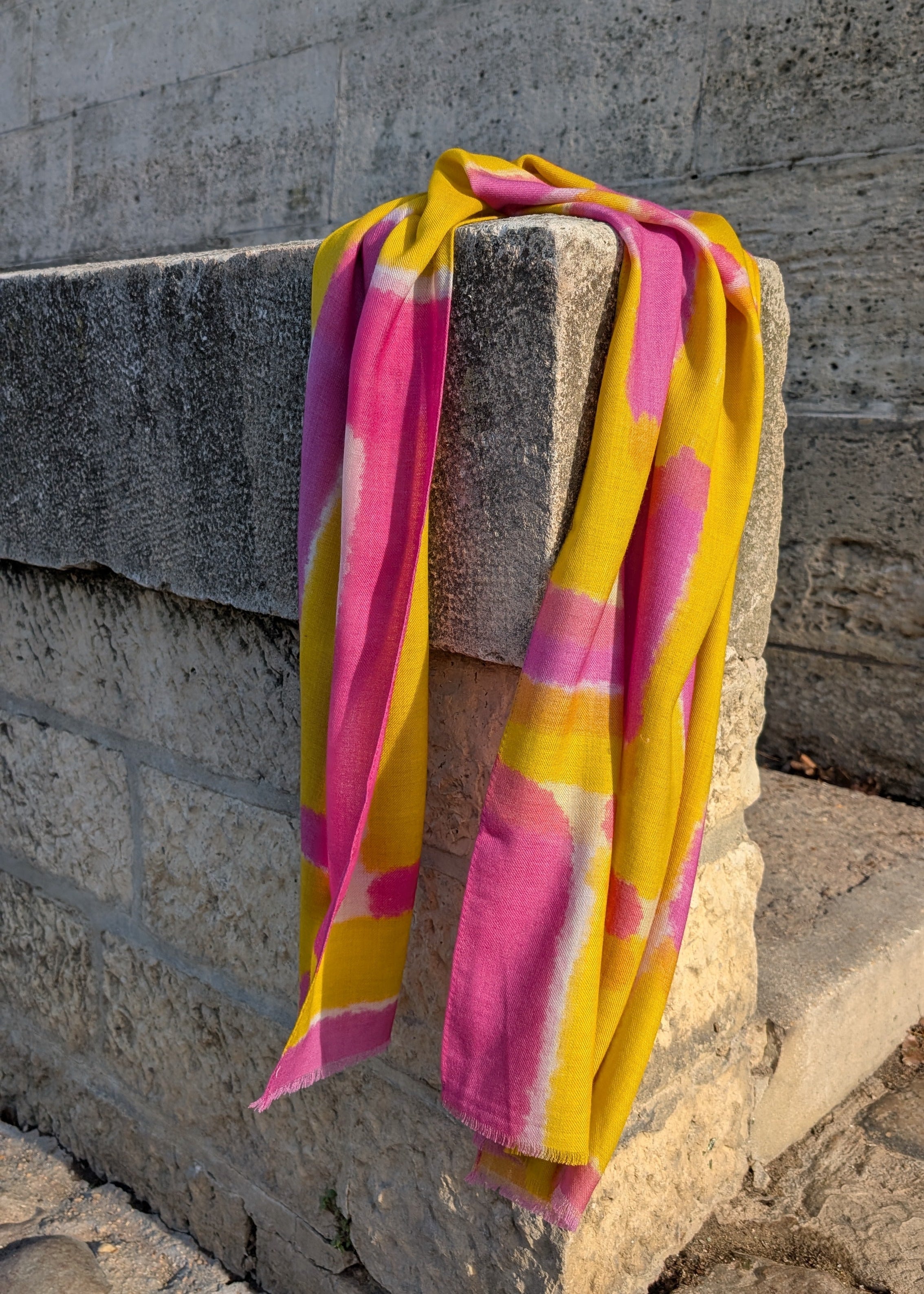 Yellow and pink scarf draped over a stone ledge.