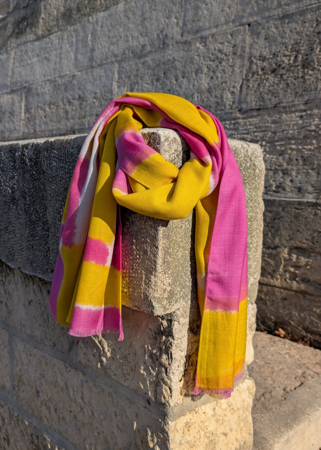 Pink and yellow scarf draped over a stone wall