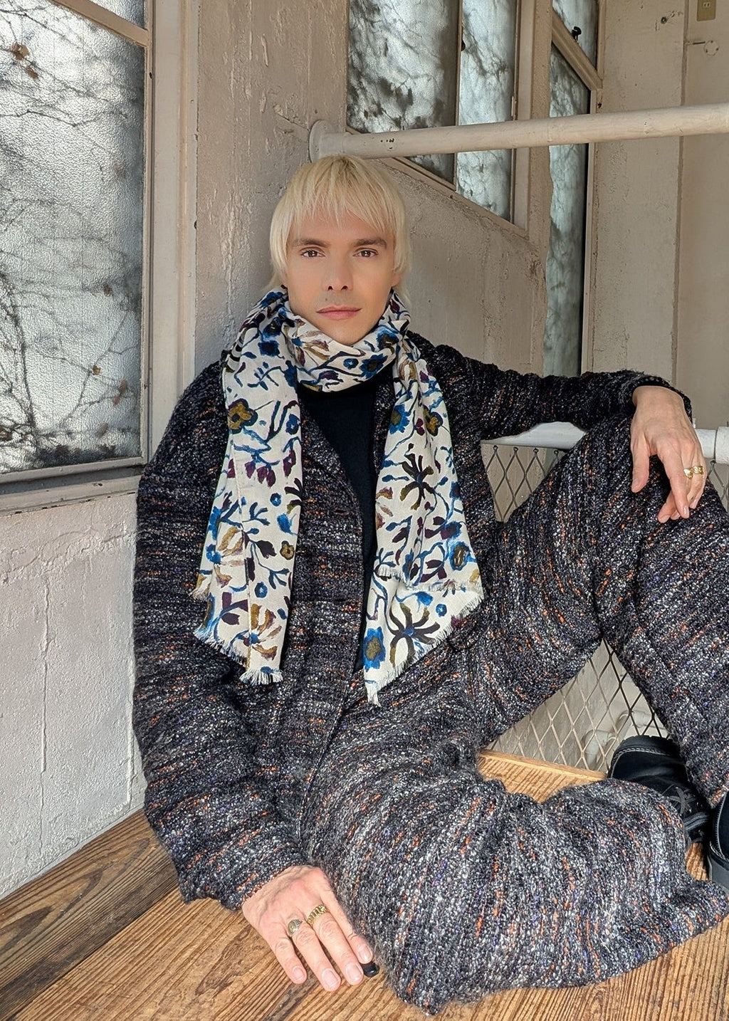 Sammy Voigtwearing a garden patterned wool scarf sitting on a wooden floor.