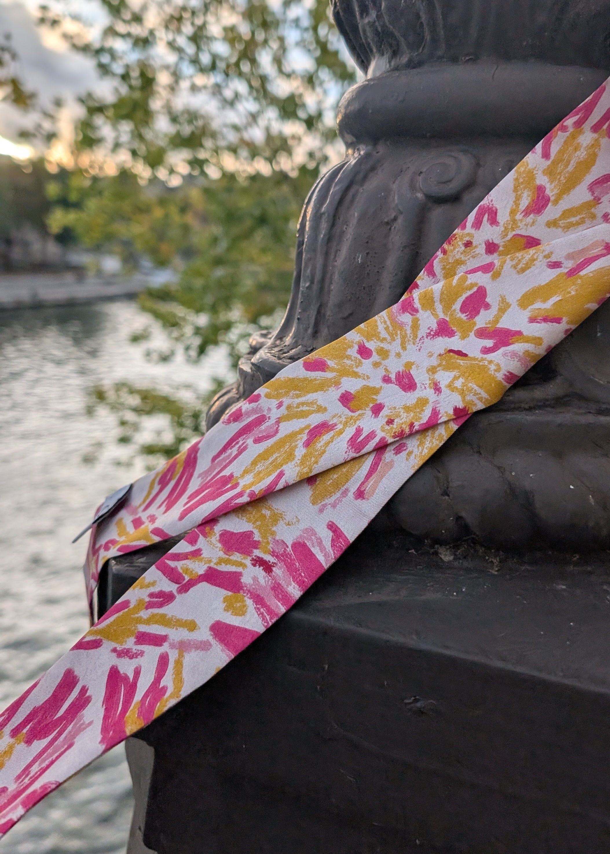 Pink and yellow patterned strap held over a statue with a blurred natural background